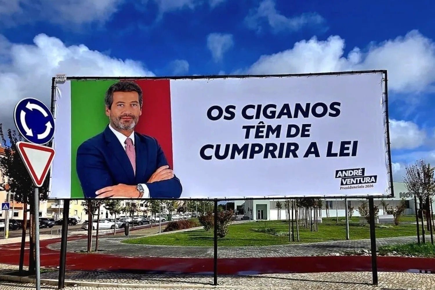 Cartaz de campanha com fotografia de André Ventura, candidato presidencial, ao lado da frase 'Os ciganos têm de cumprir a lei', destacando a polémica referida no artigo.