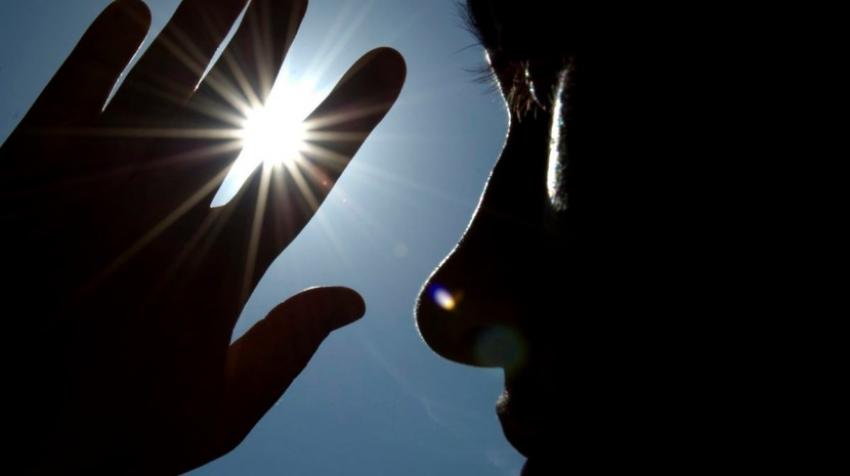 Termómetro a indicar temperatura elevada sob céu azul com sol intenso, ilustrando risco elevado de radiação ultravioleta.